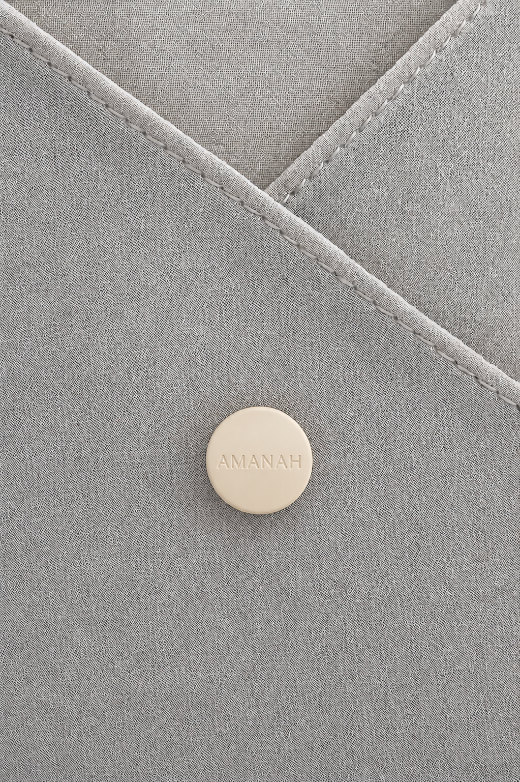 Close-up of a beige AMANAH hijab magnet placed on hijab fabric.