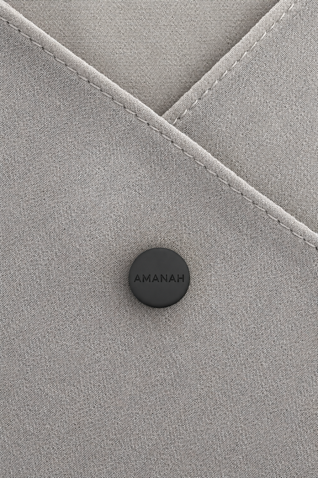 Close-up of a black AMANAH hijab magnet placed on hijab fabric.