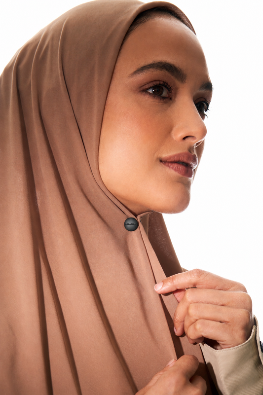 Close-up of a woman wearing with a small black AMANAH hijab magnet.