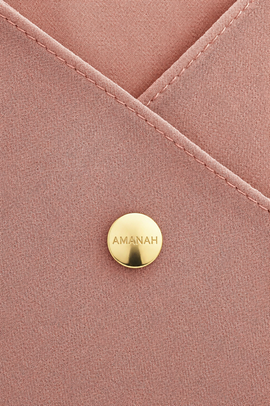 Close-up of a gold AMANAH hijab magnet placed on hijab fabric.