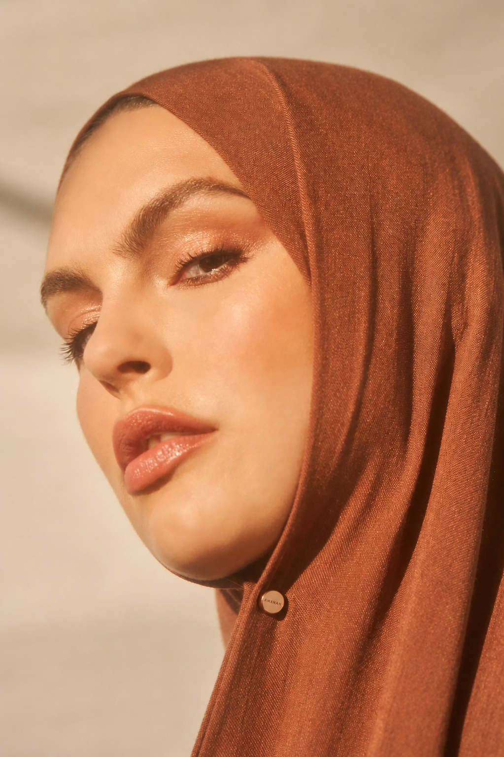 Close-up of a woman wearing with a small gold AMANAH hijab magnet.