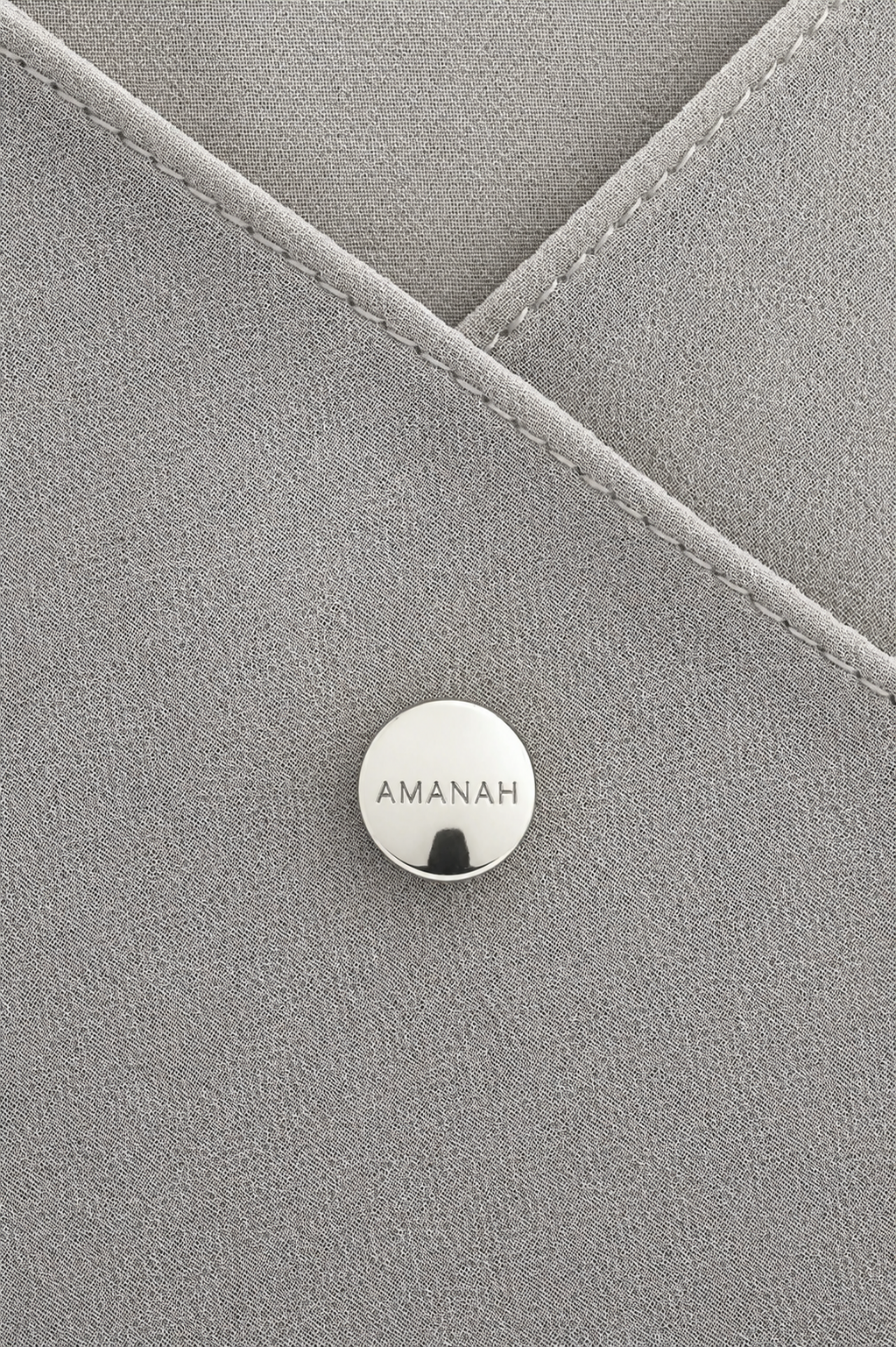Close-up of a silver AMANAH hijab magnet placed on hijab fabric.