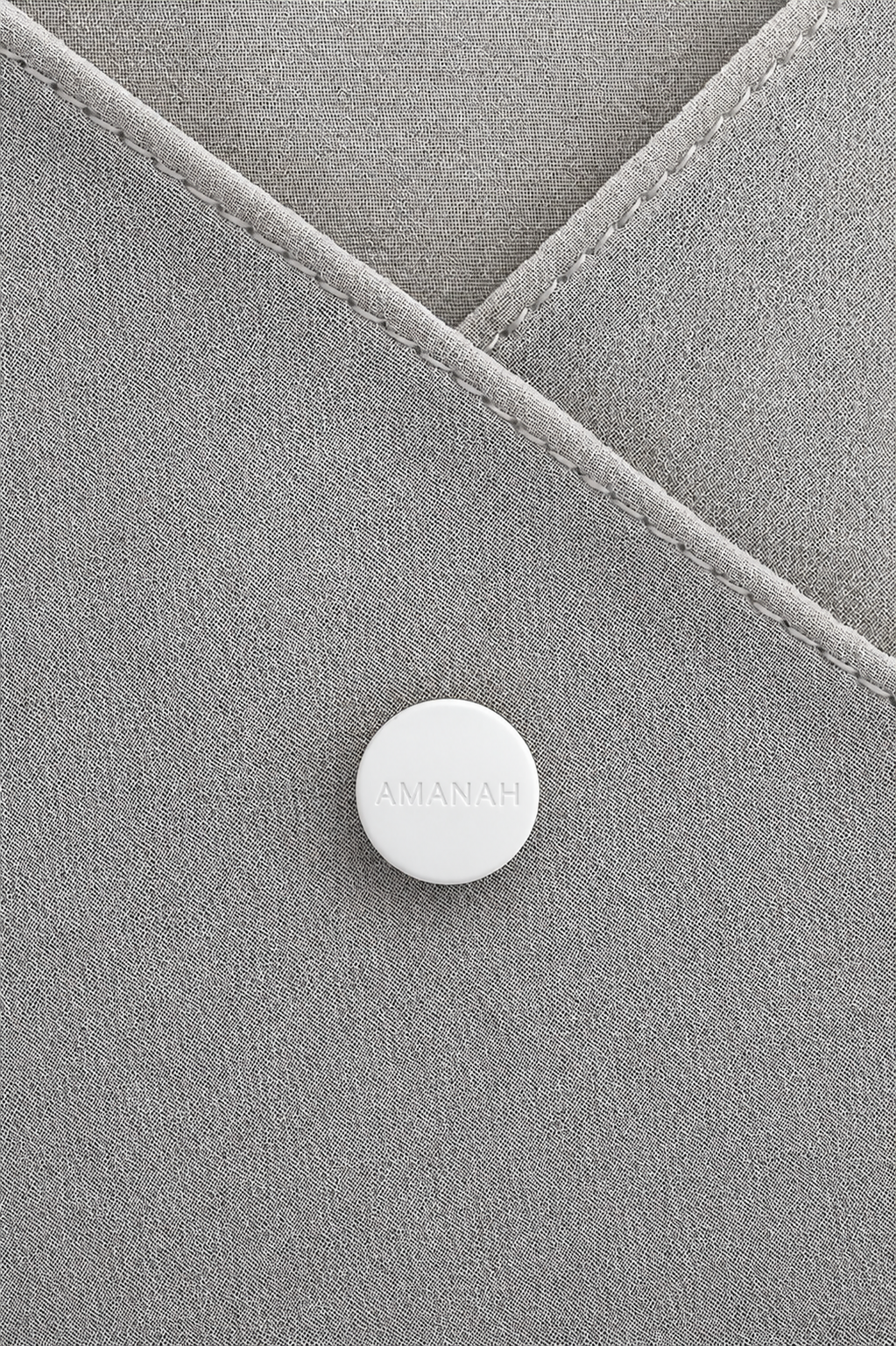 Close-up of a white AMANAH hijab magnet placed on hijab fabric.
