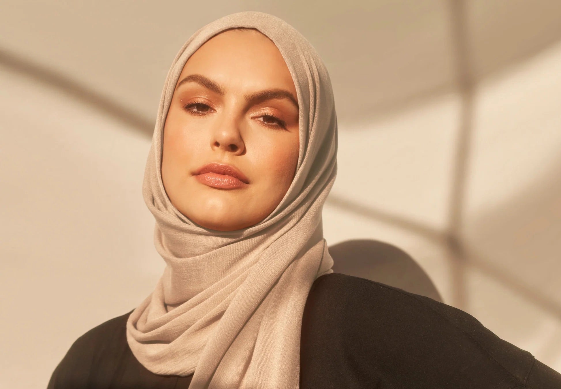 Hijabi woman wearing a beige jersey hijab by Amanah styled for calm everyday wear